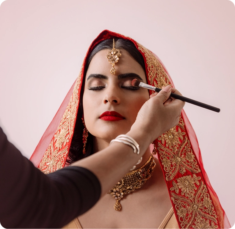 Bride in red veil having makeup applied.
